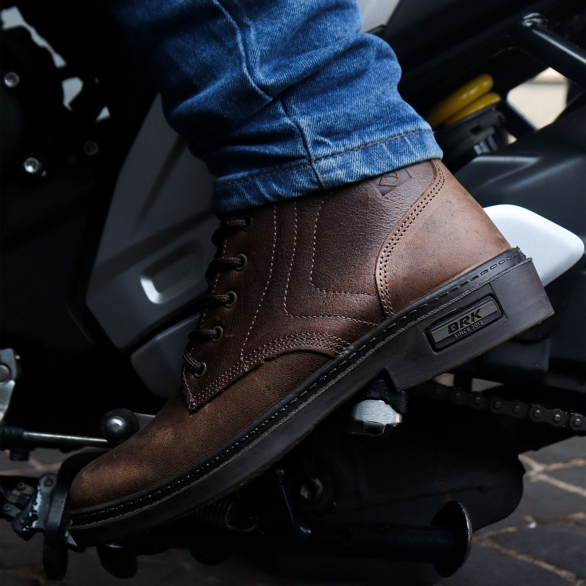 Botas marrons BRK em couro com cadarço, usadas com calça jeans em motocicleta preta